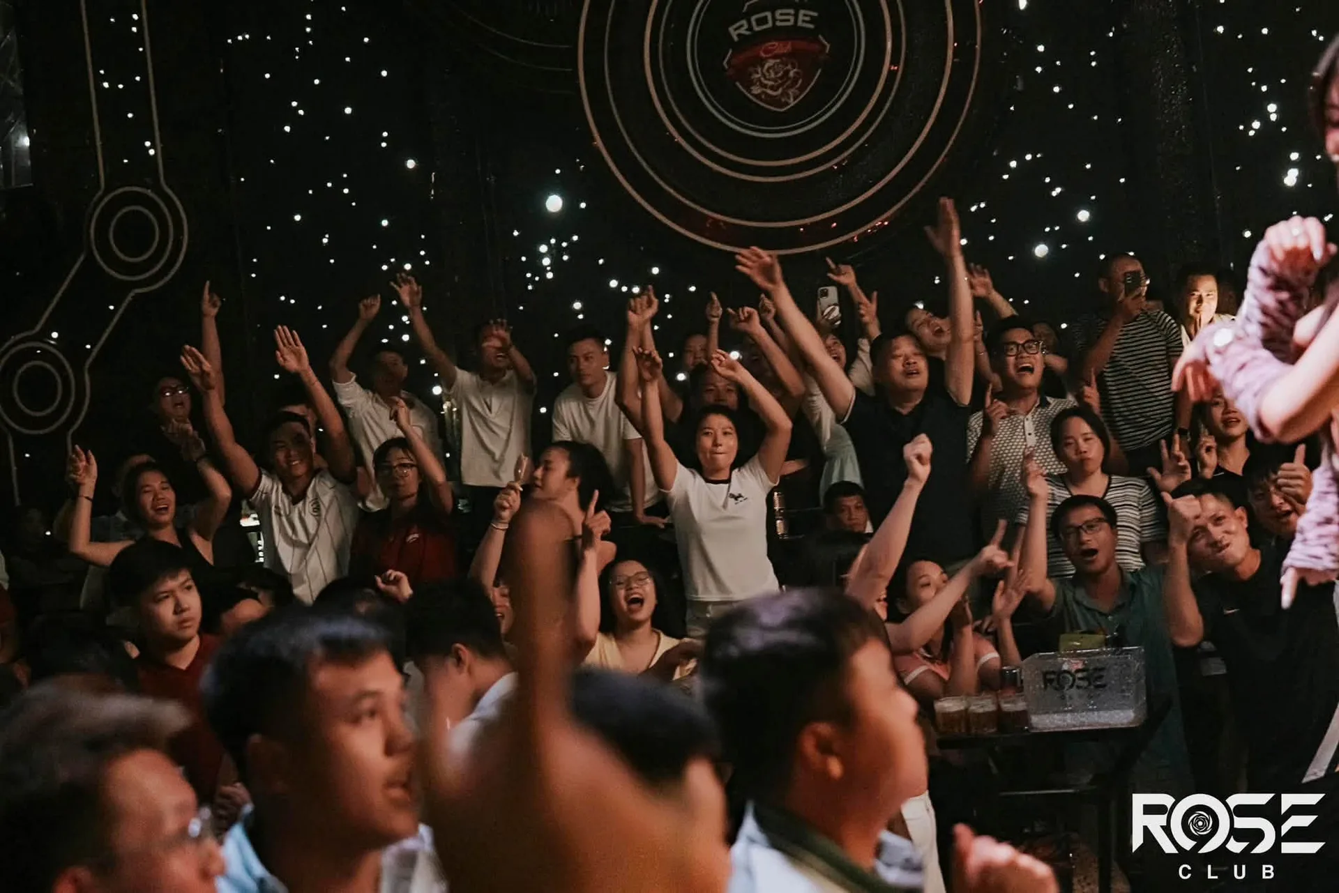Cả sàn giơ tay dưới đĩa huy hiệu ROSE